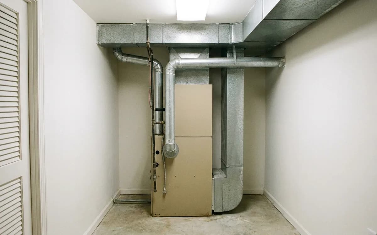 Gas furnace from the 1990s installed in a finished basement utility closet
