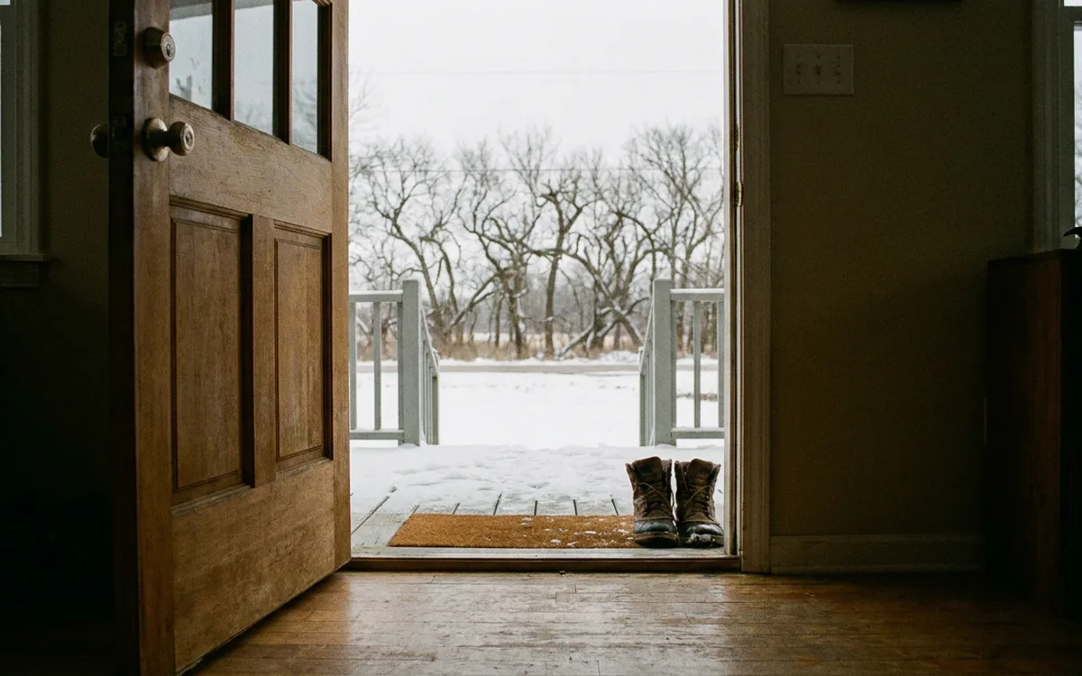 Open front door looking out onto a snowy porch on a winter morning