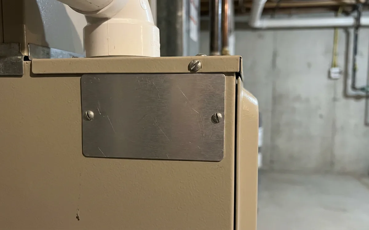 Blank metal rating plate on a high-efficiency furnace with PVC venting above